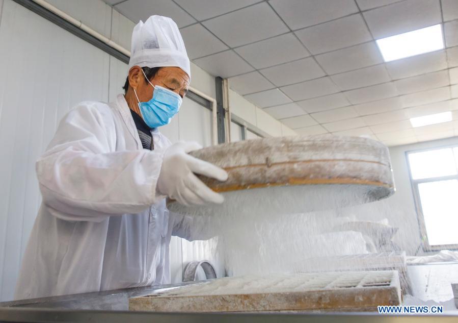 A worker makes rice cakes at a food factory in Zhuangzhi Village of Haian, east China's Jiangsu Province, Jan. 16, 2021. Workers in Haian are busy making rice cakes to meet customers' growing demands as the Spring Festival approaches. (Photo by Xiang Zhonglin/Xinhua)