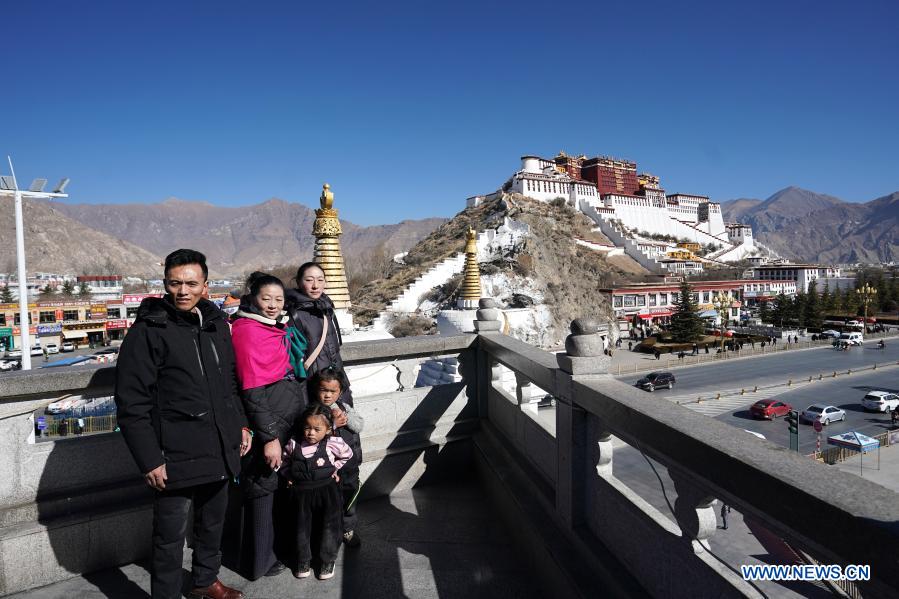 Visitors pose for a photo with the Potala Palace, a UNESCO world heritage site dating back to the 7th century, from an observation point in Lhasa, capital of southwest China's Tibet Autonomous Region, Jan. 18, 2021. (Xinhua/Zhan Yan)