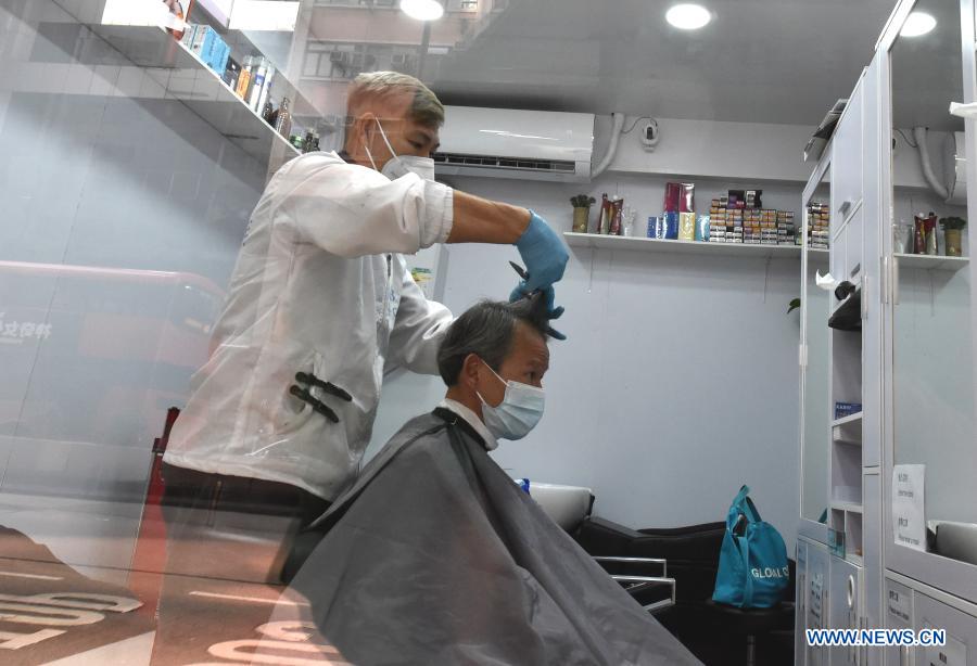 A hairdresser cuts hair for a customer in south China's Hong Kong, Jan. 18, 2021. Hong Kong's Center for Health Protection (CHP) reported 107 additional confirmed cases of COVID-19 on Monday, a new high in about one month. The new cases included 102 local infections and five imported ones, taking its total tally to 9,664. More than 40 of the new local cases were untraceable and there were about 50 cases tested positive preliminarily, according to a CHP press briefing. (Xinhua/Lo Ping Fai)