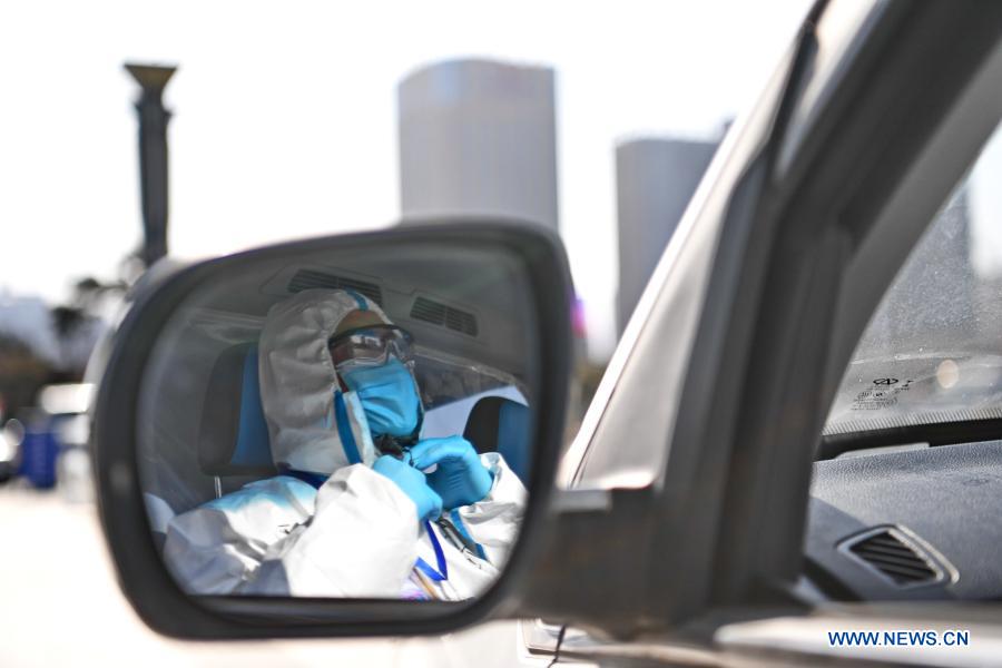 Ride-hailing driver volunteer Fan Yuejia adjusts his protective suit to prepare for the next free ride service amid the COVID-19 pandemic in Shijiazhuang, north China's Hebei Province, Jan. 18, 2021. As all other public transportation services in Shijiazhuang were suspended for COVID-19 prevention and control purposes, local ride-hailing drivers have stepped forward and volunteered to help. Headed by 36-year-old Fan Yuejia, the 800-strong team of volunteer drivers is providing free rides to travellers arriving in the city in the run-up to the Chinese Lunar New Year. (Xinhua/Zhu Xudong)