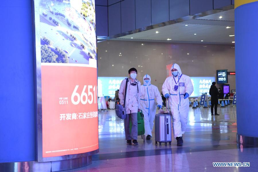 Ride-hailing driver volunteer Fan Yuejia (R) accompanies a returning passenger out of Shijiazhuang Railway Station for a free ride service amid the COVID-19 pandemic in Shijiazhuang, north China's Hebei Province, Jan. 18, 2021. As all other public transportation services in Shijiazhuang were suspended for COVID-19 prevention and control purposes, local ride-hailing drivers have stepped forward and volunteered to help. Headed by 36-year-old Fan Yuejia, the 800-strong team of volunteer drivers is providing free rides to travellers arriving in the city in the run-up to the Chinese Lunar New Year. (Xinhua/Zhu Xudong)