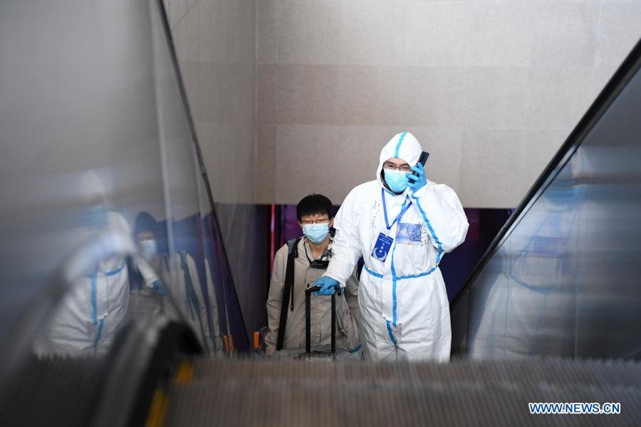 Ride-hailing driver volunteer Fan Yuejia accompanies a returning passenger out of Shijiazhuang Railway Station for a free ride service amid the COVID-19 pandemic in Shijiazhuang, north China's Hebei Province, Jan. 18, 2021. As all other public transportation services in Shijiazhuang were suspended for COVID-19 prevention and control purposes, local ride-hailing drivers have stepped forward and volunteered to help. Headed by 36-year-old Fan Yuejia, the 800-strong team of volunteer drivers is providing free rides to travellers arriving in the city in the run-up to the Chinese Lunar New Year. (Xinhua/Zhu Xudong)