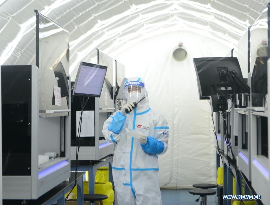 Staff member Ou Rong talks with his colleagues outside the cabin of extracting nucleic acid through a walkie-talkie at the nucleic acid test laboratory named Huoyan, or Fire Eye, in Shijiazhuang, north China's Hebei Province, Jan. 18, 2021. On Jan. 8, a nucleic acid test laboratory named Huoyan, or Fire Eye, was built in only 10 hours and put into use in 21 hours in Shijiazhuang. It can test up to 1 million samples a day, significantly improving the city's testing capability. (Xinhua/Jin Haoyuan)