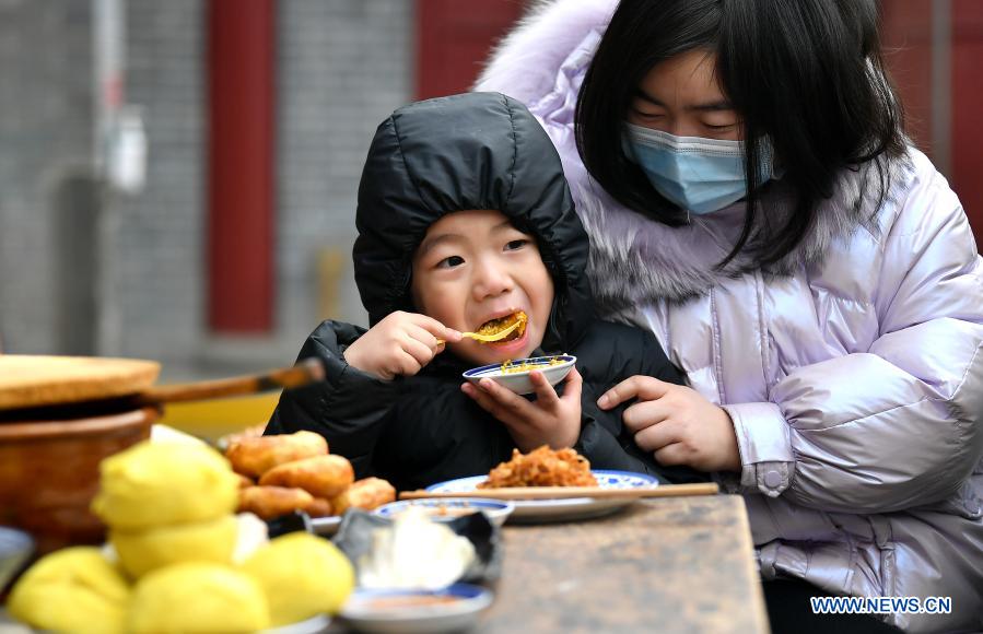 A boy eats Laba snack at Yongxingfang in Xi'an, northwest China's Shaanxi Province, Jan. 20, 2020. The Laba Festival, literally the eighth day of the 12th lunar month, is considered a prelude to the Spring Festival, or Chinese Lunar New Year. (Xinhua/Liu Xiao)