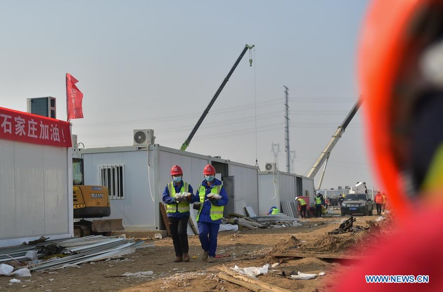 Luo Chang'an(L) and Luo Yandong bring lunch back at the construction site of the Huangzhuang Apartment quarantine center in Shijiazhuang, north China's Hebei Province, Jan. 21, 2021. Luo Yandong, a 22-year-old junior of Wuhan Technical College of Communications, started his internship at Second Engineering Co., Ltd. of China Railway First Group three months ago. He now participates in the construction of Huangzhuang Apartment quarantine center where his father Luo Chang'an is also a worker. Located at the junction of Zhengding County and Gaocheng District in Shijiazhuang, the Huangzhuang Apartment COVID-19 quarantine center project covers an area of 658 mu (about 43.87 hectares) with a capacity of 4,156 rooms, which will be used to accommodate close contacts and sub-close contacts of confirmed COVID-19 patients. (Xinhua/Yang Shiyao)