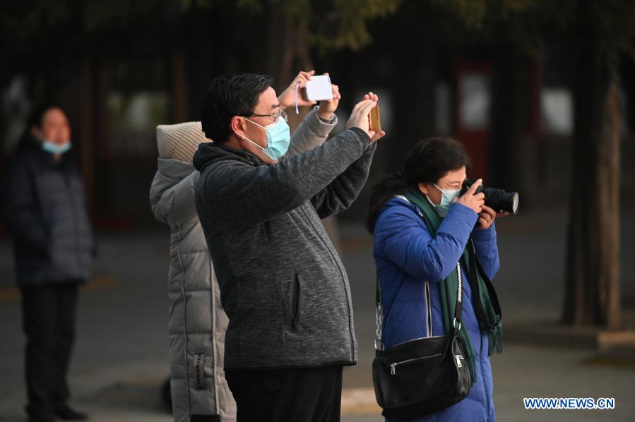 Tourists take photos during sunset at the Summer Palace in Beijing, capital of China, Jan. 21, 2021. (Photo by Hu Zhixuan/Xinhua)