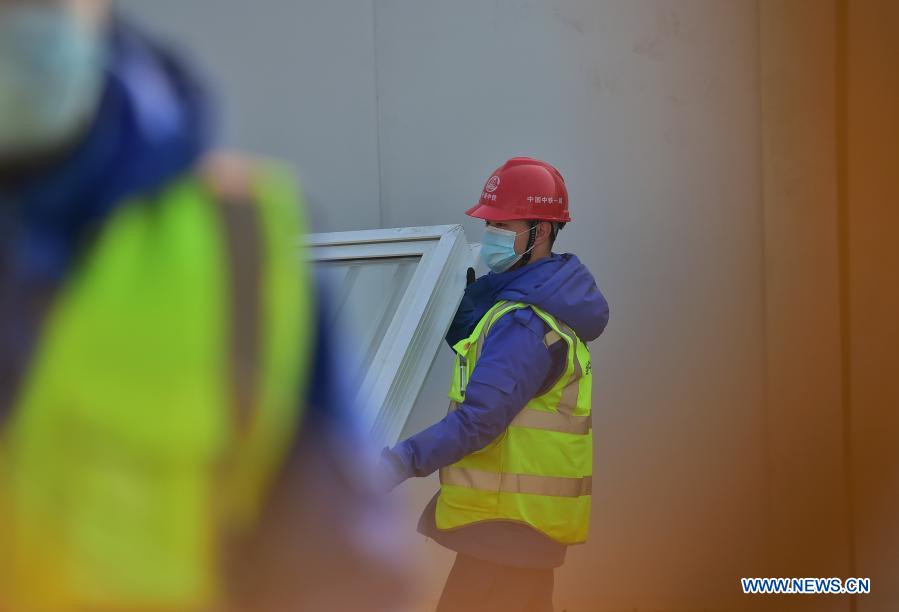 Luo Yandong carries windows at the construction site of the Huangzhuang Apartment quarantine center in Shijiazhuang, north China's Hebei Province, Jan. 21, 2021. Luo Yandong, a 22-year-old junior of Wuhan Technical College of Communications, started his internship at Second Engineering Co., Ltd. of China Railway First Group three months ago. He now participates in the construction of Huangzhuang Apartment quarantine center where his father Luo Chang'an is also a worker. Located at the junction of Zhengding County and Gaocheng District in Shijiazhuang, the Huangzhuang Apartment COVID-19 quarantine center project covers an area of 658 mu (about 43.87 hectares) with a capacity of 4,156 rooms, which will be used to accommodate close contacts and sub-close contacts of confirmed COVID-19 patients. (Xinhua/Yang Shiyao)