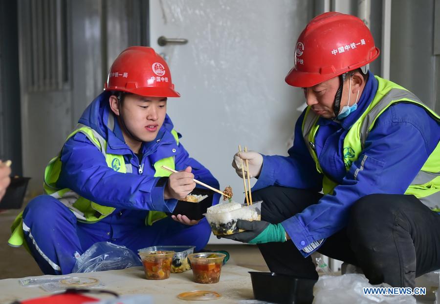 Luo Chang'an(R) and Luo Yandong have lunch at the construction site of the Huangzhuang Apartment quarantine center in Shijiazhuang, north China's Hebei Province, Jan. 21, 2021. Luo Yandong, a 22-year-old junior of Wuhan Technical College of Communications, started his internship at Second Engineering Co., Ltd. of China Railway First Group three months ago. He now participates in the construction of Huangzhuang Apartment quarantine center where his father Luo Chang'an is also a worker. Located at the junction of Zhengding County and Gaocheng District in Shijiazhuang, the Huangzhuang Apartment COVID-19 quarantine center project covers an area of 658 mu (about 43.87 hectares) with a capacity of 4,156 rooms, which will be used to accommodate close contacts and sub-close contacts of confirmed COVID-19 patients. (Xinhua/Yang Shiyao)