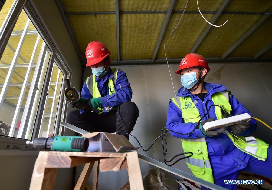 Luo Chang'an(L) and Luo Yandong work at the construction site of the Huangzhuang Apartment quarantine center in Shijiazhuang, north China's Hebei Province, Jan. 21, 2021. Luo Yandong, a 22-year-old junior of Wuhan Technical College of Communications, started his internship at Second Engineering Co., Ltd. of China Railway First Group three months ago. He now participates in the construction of Huangzhuang Apartment quarantine center where his father Luo Chang'an is also a worker. Located at the junction of Zhengding County and Gaocheng District in Shijiazhuang, the Huangzhuang Apartment COVID-19 quarantine center project covers an area of 658 mu (about 43.87 hectares) with a capacity of 4,156 rooms, which will be used to accommodate close contacts and sub-close contacts of confirmed COVID-19 patients. (Xinhua/Yang Shiyao)