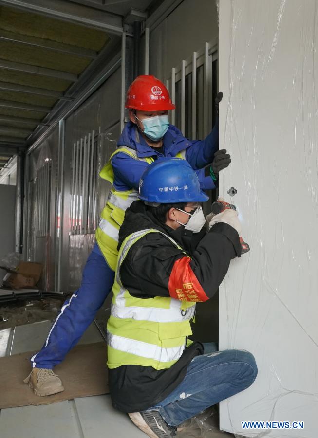 Luo Yandong(back) works with his colleague at the construction site of the Huangzhuang Apartment quarantine center in Shijiazhuang, north China's Hebei Province, Jan. 21, 2021. Luo Yandong, a 22-year-old junior of Wuhan Technical College of Communications, started his internship at Second Engineering Co., Ltd. of China Railway First Group three months ago. He now participates in the construction of Huangzhuang Apartment quarantine center where his father Luo Chang'an is also a worker. Located at the junction of Zhengding County and Gaocheng District in Shijiazhuang, the Huangzhuang Apartment COVID-19 quarantine center project covers an area of 658 mu (about 43.87 hectares) with a capacity of 4,156 rooms, which will be used to accommodate close contacts and sub-close contacts of confirmed COVID-19 patients. (Xinhua/Yang Shiyao)