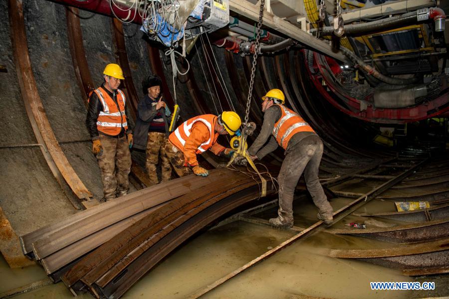 Workers transport steel arches at the construction site of Tianshan Shengli tunnel in northwest China's Xinjiang Uygur Autonomous Region, Feb. 4, 2021. Tianshan Shengli tunnel, with a total length of about 22 kilometers, is currently the longest highway tunnel under construction in China. Started in 2020, the tunnel, a six-year project on the Urumqi-Yuli highway, passes through a cold and high altitude zone, with harsh climate and geological condition. After completion and opened to traffic, it will provide safer and more convenient travel to the passengers and promote local economic and social development. (Xinhua/Hu Huhu)