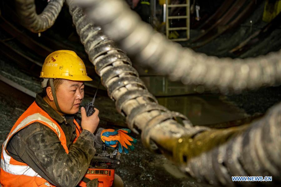 A worker talks with his colleague by walkie-talkie at the construction site of Tianshan Shengli tunnel in northwest China's Xinjiang Uygur Autonomous Region, Feb. 4, 2021. Tianshan Shengli tunnel, with a total length of about 22 kilometers, is currently the longest highway tunnel under construction in China. Started in 2020, the tunnel, a six-year project on the Urumqi-Yuli highway, passes through a cold and high altitude zone, with harsh climate and geological condition. After completion and opened to traffic, it will provide safer and more convenient travel to the passengers and promote local economic and social development. (Xinhua/Hu Huhu)