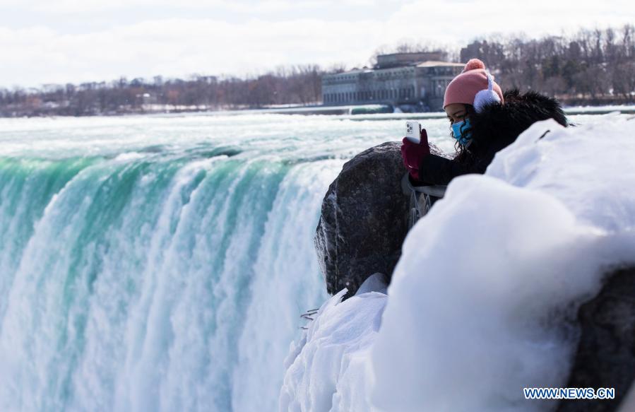 A visitor wearing a face mask takes photos in Niagara Falls, Ontario, Canada, on March 2, 2021. (Photo by Zou Zheng/Xinhua)