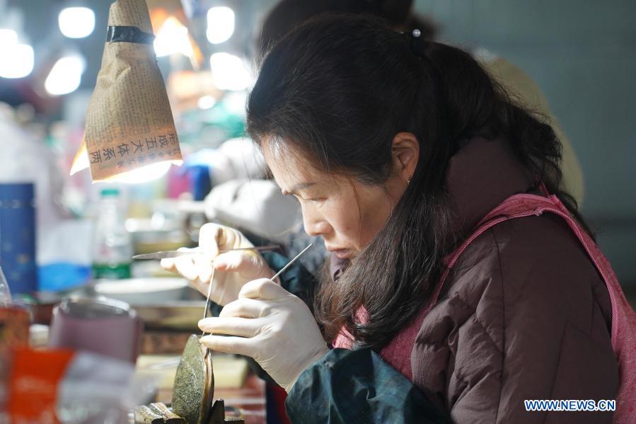 A worker inserts a nucleus into a mussel to form a pearl in a cultivation base in Tajiang Village of Wannian County, east China's Jiangxi Province, March 3, 2021. In Wannian County, there are about 3,000 women working in pearl cultivation industry. Many of them once lived in poor households, and took up their posts after free training. Nowadays, their per capita income has increased by 70,000 to 80,000 yuan (about 10,822 to 12,368 U.S. dollars) each year. (Xinhua/Zhou Mi)