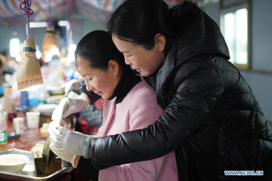 A worker gets trained to insert a nucleus into a mussel to form a pearl in a cultivation base in Tajiang Village of Wannian County, east China's Jiangxi Province, March 3, 2021. In Wannian County, there are about 3,000 women working in pearl cultivation industry. Many of them once lived in poor households, and took up their posts after free training. Nowadays, their per capita income has increased by 70,000 to 80,000 yuan (about 10,822 to 12,368 U.S. dollars) each year. (Xinhua/Zhou Mi)