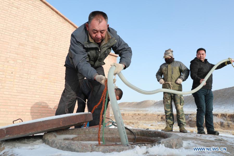 Gu Zhengli (1st L) and his colleagues install a pump at a water supply point in Dahe Township, Yugu Autonomous County of Sunan, northwest China's Gansu Province, March 20, 2021. Gu Zhengli, 59, has been working at the frontline of Tanggaer water conservancy project in Dahe Township for 42 years, safeguarding the safety of the drinking water for local people and livestock. As the annual rainfall in the town is only 150 to 300 millimeters, Tanggaer water conservancy project is literally the lifeline for local herdsmen. Every morning, Gu gets up early and operates a pump to move water from the pumping station at the foot of the mountain to a reservoir at the top. Then he climbs to the top of the mountain at about 7 o'clock and opens the valve, letting the water in the reservoir flow to each water supply point through 7 pipelines. After that, he rides a motorcycle to 52 water supply points to check if everything runs well. In the past 42 years, Gu has been working like this. Local herdsmen always see him busy on the way along the water conservancy project. Thanks to the efforts of Gu and his colleagues, people in the area now can not only enjoy much safer water but also achieve a balance between grass and livestock ahead of schedule. At a drinking well along the water conservancy project, local herdsmen wrote a sign which says 