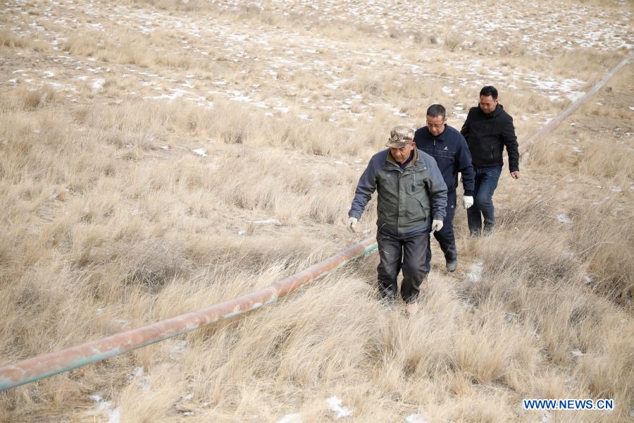 Gu Zhengli (front) and his colleagues are on the way of an inspection tour in Dahe Township, Yugu Autonomous County of Sunan, northwest China's Gansu Province, March 20, 2021. Gu Zhengli, 59, has been working at the frontline of Tanggaer water conservancy project in Dahe Township for 42 years, safeguarding the safety of the drinking water for local people and livestock. As the annual rainfall in the town is only 150 to 300 millimeters, Tanggaer water conservancy project is literally the lifeline for local herdsmen. Every morning, Gu gets up early and operates a pump to move water from the pumping station at the foot of the mountain to a reservoir at the top. Then he climbs to the top of the mountain at about 7 o'clock and opens the valve, letting the water in the reservoir flow to each water supply point through 7 pipelines. After that, he rides a motorcycle to 52 water supply points to check if everything runs well. In the past 42 years, Gu has been working like this. Local herdsmen always see him busy on the way along the water conservancy project. Thanks to the efforts of Gu and his colleagues, people in the area now can not only enjoy much safer water but also achieve a balance between grass and livestock ahead of schedule. At a drinking well along the water conservancy project, local herdsmen wrote a sign which says 