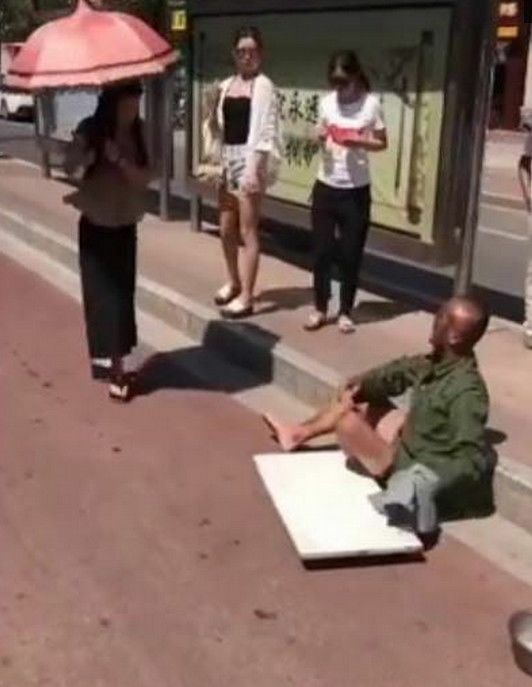 乞丐爬到女子面前,抓住女子的脚进行乞讨,女子拒绝后狠狠踩一脚