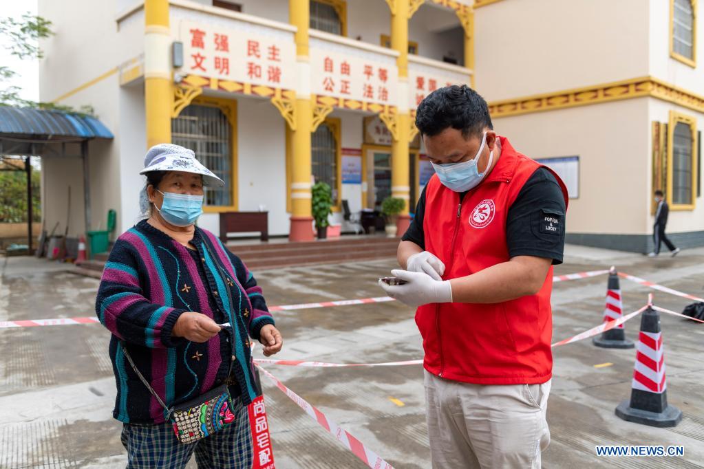 A volunteer registers information for a senior woman at a nucleic acid testing site in Ruili City, southwest China's Yunnan Province, April 6, 2021. Frontline medical workers, epidemic prevention and control personnel, border patrol personnel and volunteers from all walks of life work hard to control the spread of the novel coronavirus after new cluster infections were reported late March. (Xinhua/Chen Xinbo)