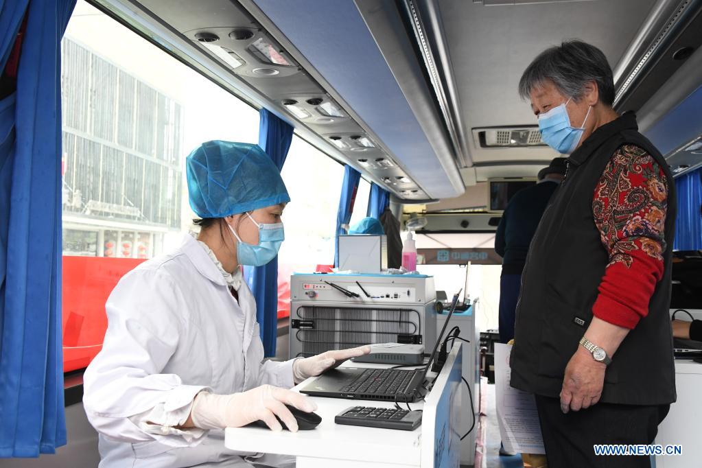 A medical worker registers the information for a woman before inoculation in a mobile vaccination vehicle in Haidian District of Beijing, capital of China, April 11, 2021. Beijing and Shanghai have deployed mobile vaccination vehicles in downtown areas. The bus-like facilities, equipped with vaccination stations, medical refrigerators and first-aid equipment, have been rolled out to save time and improve inoculation efficiency. (Xinhua/Ren Chao)