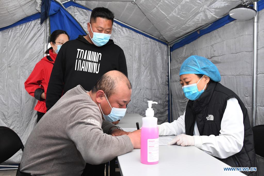 A man signs informed consent paper in a tent outside a mobile vaccination vehicle in Haidian District of Beijing, capital of China, April 11, 2021. Beijing and Shanghai have deployed mobile vaccination vehicles in downtown areas. The bus-like facilities, equipped with vaccination stations, medical refrigerators and first-aid equipment, have been rolled out to save time and improve inoculation efficiency. (Xinhua/Ren Chao)