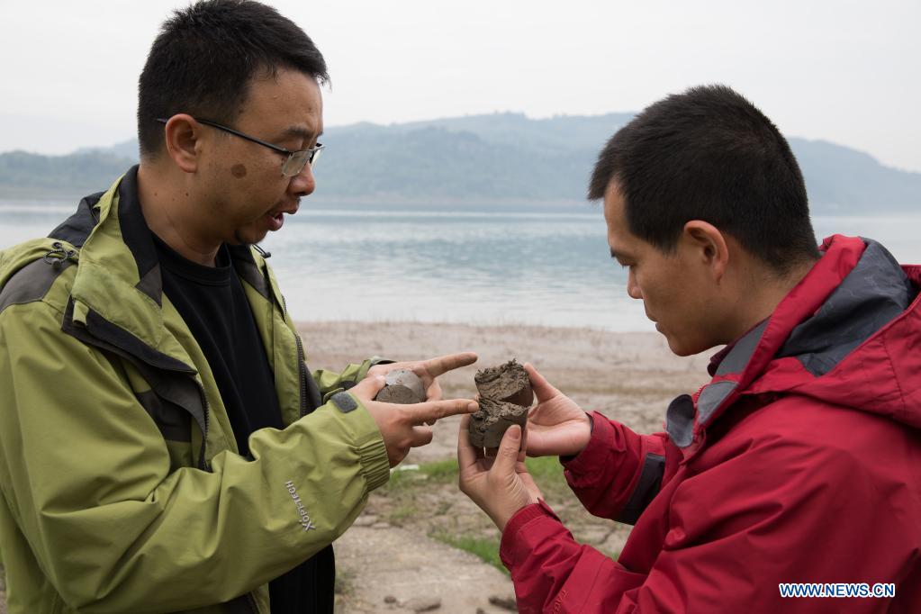 Researchers discuss the characteristic of sediments at water level fluctuation zone of the Three Gorges Reservoir in Zhongxian County, southwest China's Chongqing, April 10, 2021. The Three Gorges project is a vast multi-functional water-control system on the Yangtze River, China's longest waterway, with a 2,309-meter-long and 185-meter-high dam. The water levels of the reservoir area inevitably fluctuate on an annual discharge-storage cycle between 145m to 175m at the dam. The water level fluctuation zone also encounters some eco-environmental problems, including soil erosion and non-point source pollution. Researchers of the Institute of Mountain Hazards and Environment, Chinese Academy of Sciences (CAS) have conducted comprehensive investigations on soil, plants, hydrology, water quality and sediment in the area. Their study has important implications on better running the function of the Three Gorges Reservoir and the safety of local ecological environment. (Xinhua/Jin Liwang)