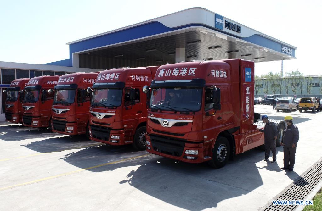 Photo taken with a drone shows workers examining five newly introduced hydrogen-powered heavy-duty trucks in the Tangshan Haigang Economic Development Zone of Tangshan, north China's Hebei Province, April 14, 2021. Five hydrogen-powered heavy-duty trucks have been introduced on Wednesday by the Tangshan Haigang Economic Development Zone. The fleet of trucks are among the zone's first attempts to optimize its industrial structure and energy consumption by gradually replacing diesel fuel with the more eco-friendly hydrogen power cells. (Xinhua/Yang Shiyao)