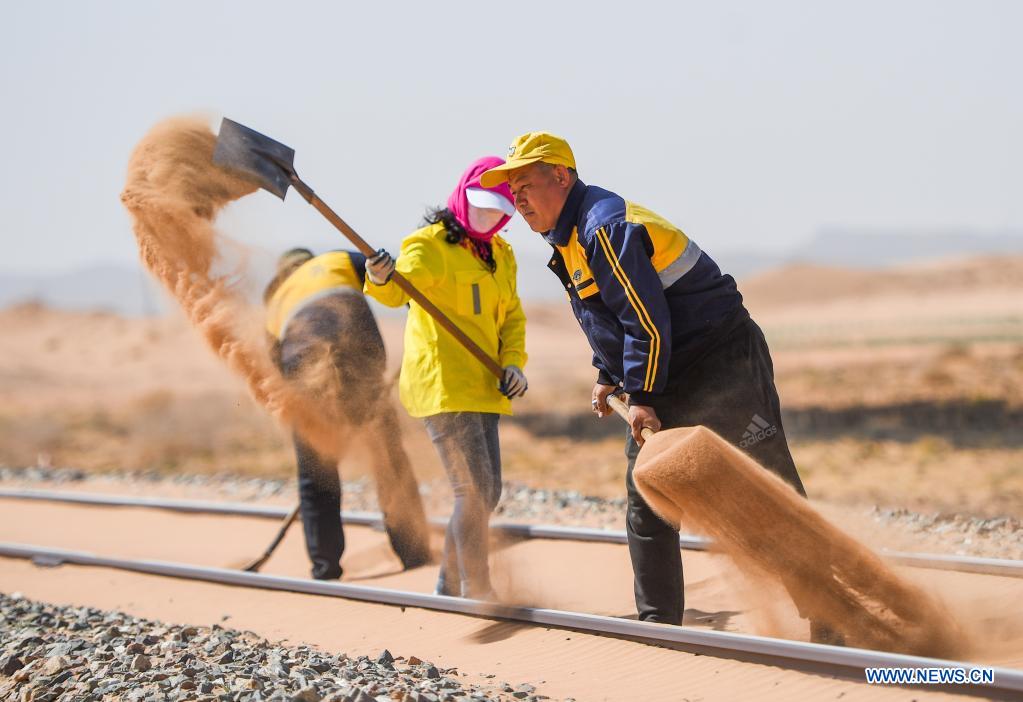 Workers remove sand along Linhe-Ceke railway in north China's Inner Mongolia Autonomous Region, April 14, 2021. With a total length of 768 kilometers, the Linhe-Ceke railway is one of the important junctions connecting Mongolia and China. Two passenger trains and nearly 40 freight trains run on it every day. In order to control the sand damage, eleven sand control stations have been set up along the Linhe-Ceke railway that traverses more than 400 kilometers of desert. The railway sand control workers are stationed here all year round to prevent the accumulation of quicksand on the railway lines and ensure the smooth railway transportation. (Xinhua/Liu Lei)