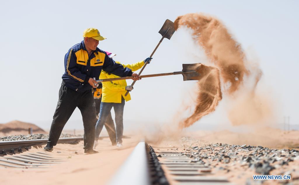 Workers remove sand along Linhe-Ceke railway in north China's Inner Mongolia Autonomous Region, April 14, 2021. With a total length of 768 kilometers, the Linhe-Ceke railway is one of the important junctions connecting Mongolia and China. Two passenger trains and nearly 40 freight trains run on it every day. In order to control the sand damage, eleven sand control stations have been set up along the Linhe-Ceke railway that traverses more than 400 kilometers of desert. The railway sand control workers are stationed here all year round to prevent the accumulation of quicksand on the railway lines and ensure the smooth railway transportation. (Xinhua/Liu Lei)