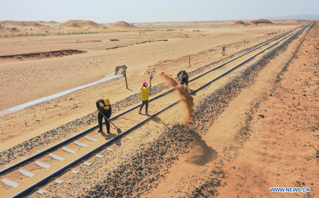 Aerial photo shows workers removing sand along Linhe-Ceke railway in north China's Inner Mongolia Autonomous Region, April 14, 2021. With a total length of 768 kilometers, the Linhe-Ceke railway is one of the important junctions connecting Mongolia and China. Two passenger trains and nearly 40 freight trains run on it every day. In order to control the sand damage, eleven sand control stations have been set up along the Linhe-Ceke railway that traverses more than 400 kilometers of desert. The railway sand control workers are stationed here all year round to prevent the accumulation of quicksand on the railway lines and ensure the smooth railway transportation. (Xinhua/Lian Zhen)