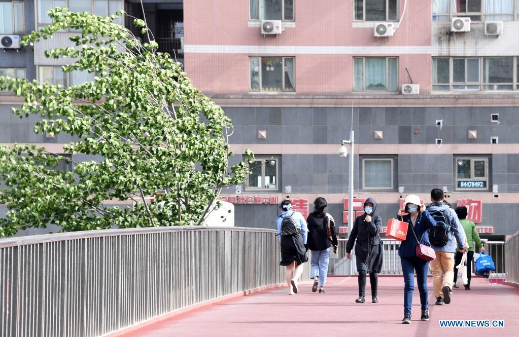 People walk on a pedestrian bridge in Beijing, capital of China, May 6, 2021. Floating sand and dust affected Beijing from Thursday noon time. (Xinhua/Ren Chao)