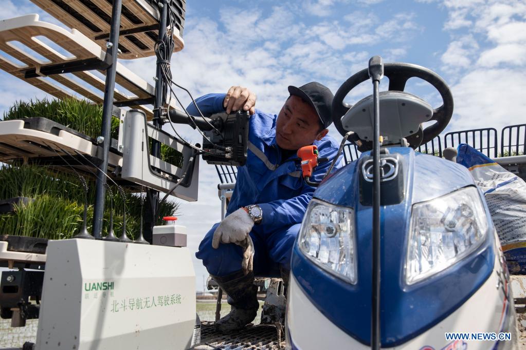 A staff member sets working route for an unmanned transplanter on a vehicle-mounted terminal tablet in a smart agriculture demonstration zone administered by Hongwei Farm Co., Ltd. of Beidahuang Group in northeast China's Heilongjiang Province, May 11, 2021. Equipped with a self-driving system based on the Beidou Navigation Satellite System (BDS), the smart transplanter can independently finish rice transplanting, avoid obstacles and turn around when needed. (Xinhua/Zhang Tao)