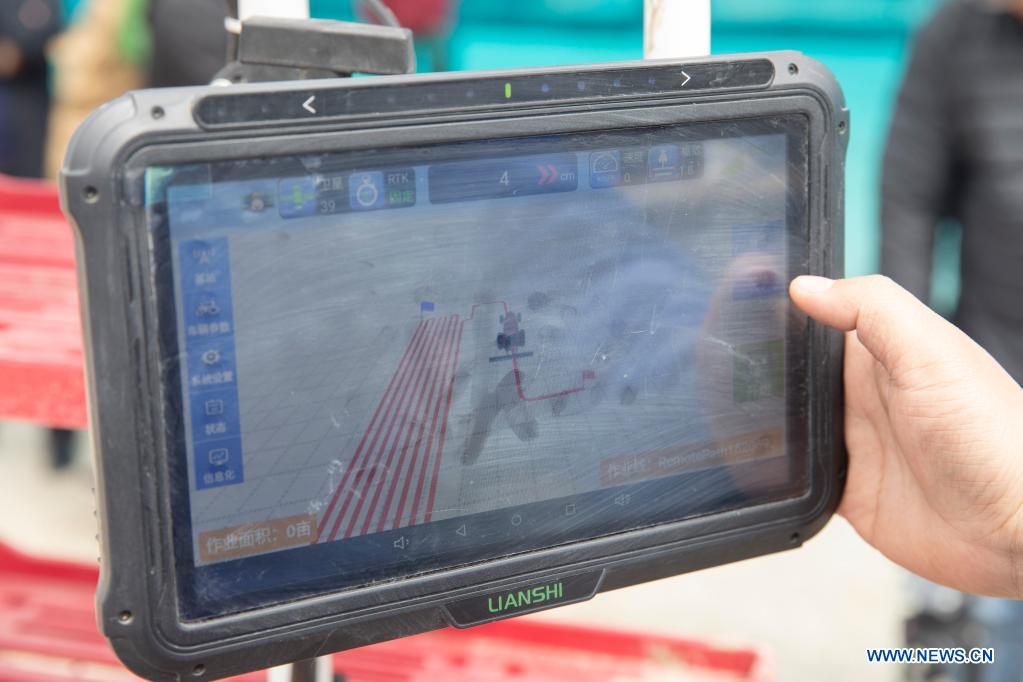 A staff member sets working route for an unmanned transplanter on a vehicle-mounted terminal tablet in a smart agriculture demonstration zone administered by Hongwei Farm Co., Ltd. of Beidahuang Group in northeast China's Heilongjiang Province, May 11, 2021. Equipped with a self-driving system based on the Beidou Navigation Satellite System (BDS), the smart transplanter can independently finish rice transplanting, avoid obstacles and turn around when needed. (Xinhua/Zhang Tao)