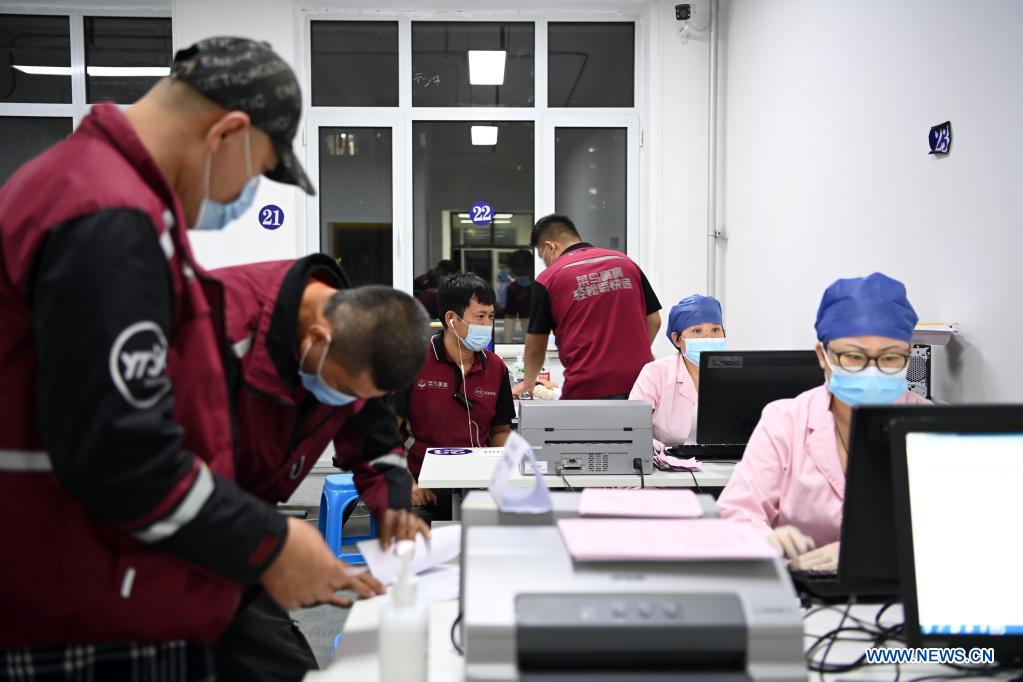 Medical workers register the information of couriers at a vaccination site in Nankai District, north China's Tianjin, May 12, 2021. A temporary vaccination site was launched to administer the second dose of COVID-19 vaccine for more than 1,000 deliverymen at Hongqi South Road of Nankai District, north China's Tianjin. The vaccination was arranged at night, in order not to affect the couriers' delivery work during the daytime. (Xinhua/Li Ran)