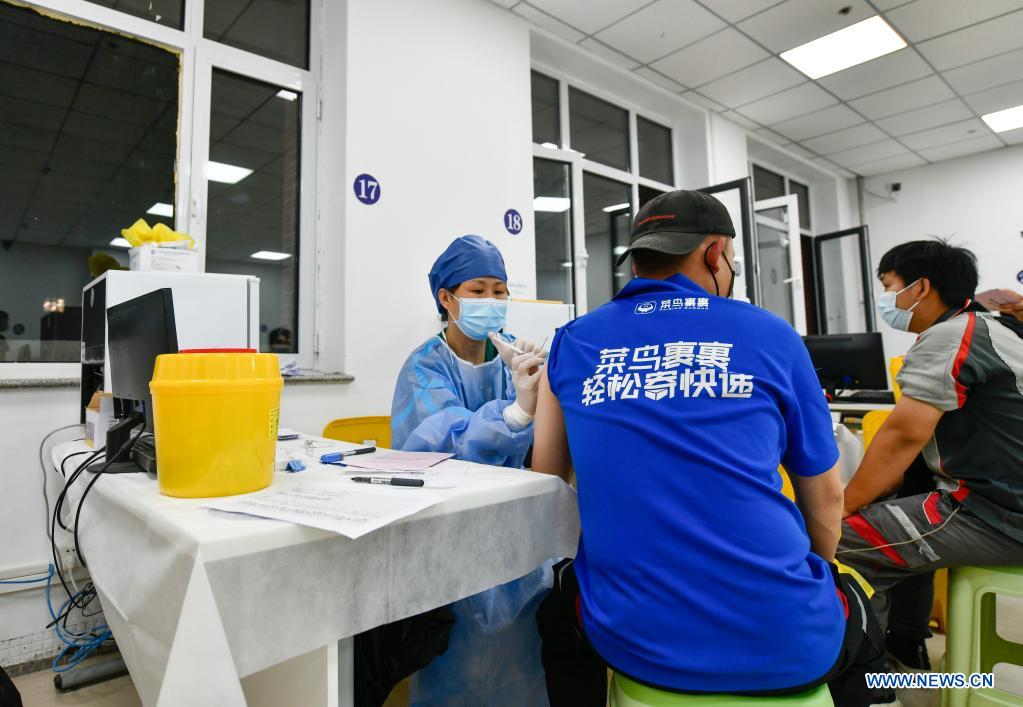 A medical worker administers a dose of COVID-19 vaccine to a courier at a vaccination site in Nankai District, north China's Tianjin, May 12, 2021. A temporary vaccination site was launched to administer the second dose of COVID-19 vaccine for more than 1,000 deliverymen at Hongqi South Road of Nankai District, north China's Tianjin. The vaccination was arranged at night, in order not to affect the couriers' delivery work during the daytime. (Xinhua/Sun Fanyue)