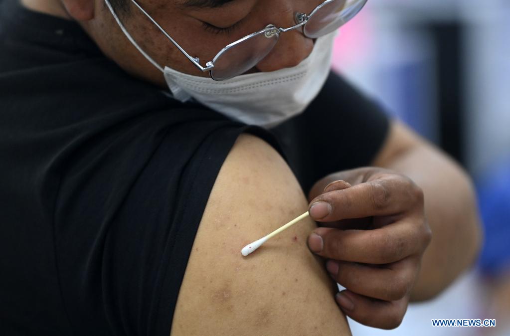 A courier presses the site of injection with a cotton swab to stop bleeding after getting administered against COVID-19 at a vaccination site in Nankai District, north China's Tianjin, May 12, 2021. A temporary vaccination site was launched to administer the second dose of COVID-19 vaccine for more than 1,000 deliverymen at Hongqi South Road of Nankai District, north China's Tianjin. The vaccination was arranged at night, in order not to affect the couriers' delivery work during the daytime. (Xinhua/Li Ran)