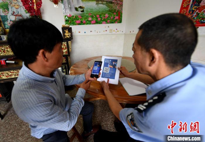 图为挂村民警引导村民扫码注册“金钟罩”反诈骗预警系统。　王东明 摄
