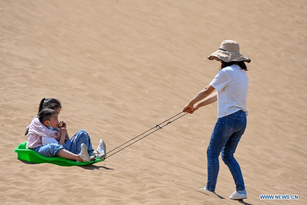Visitors experience sand sliding in Kumtag Desert in Shanshan County, northwest China's Xinjiang Uygur Autonomous Region, May 15, 2021. The county sees boom in desert tourism early May. (Xinhua/Ding Lei)