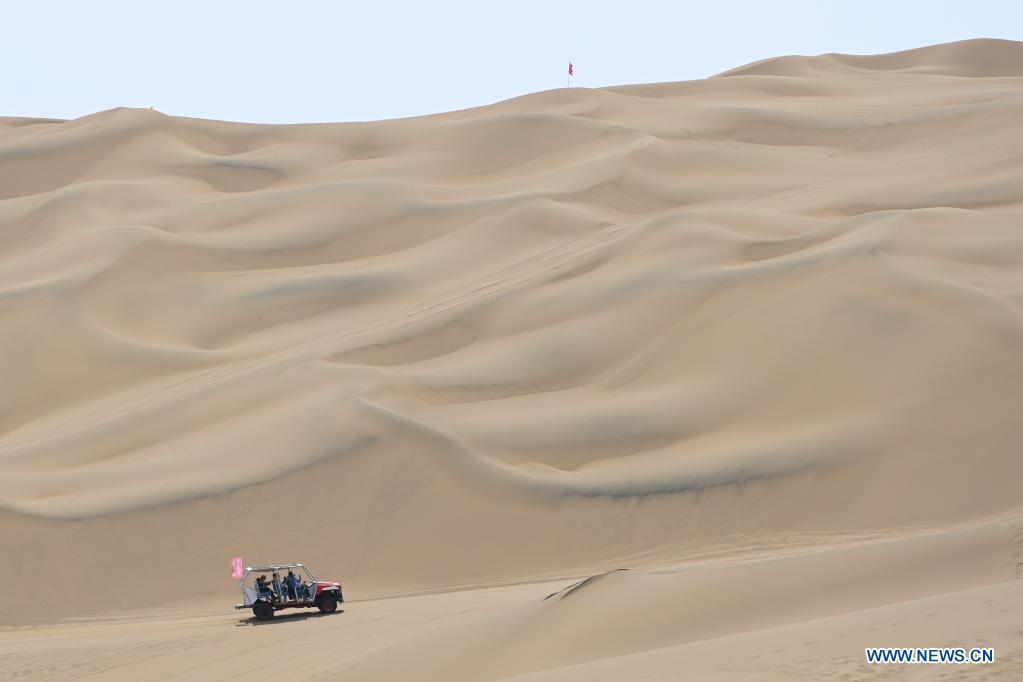 Visitors ride a sand surfing car in Kumtag Desert in Shanshan County, northwest China's Xinjiang Uygur Autonomous Region, May 16, 2021. The county sees boom in desert tourism early May. (Xinhua/Ding Lei)