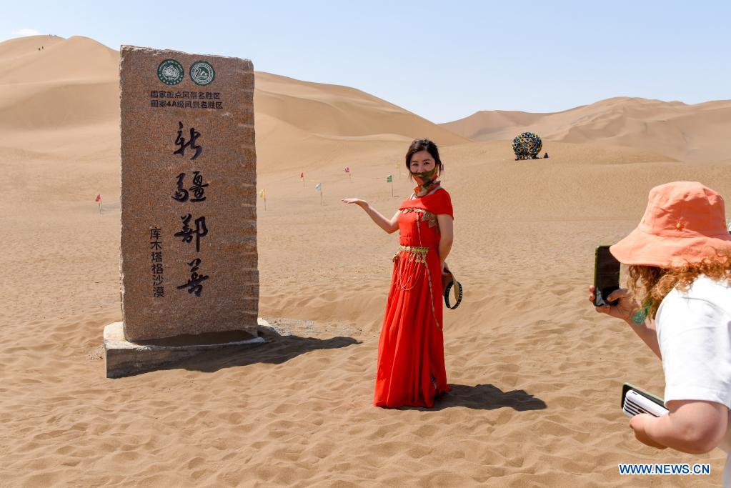 A visitor poses for photos in Kumtag Desert in Shanshan County, northwest China's Xinjiang Uygur Autonomous Region, May 15, 2021. The county sees boom in desert tourism early May. (Xinhua/Ding Lei)