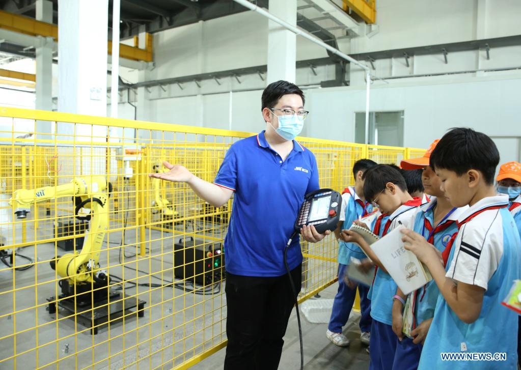 A staff member introduces the application of industry robots to students of Linhai Road Primary School at Cangzhou Laser Industry Park in Cangzhou, north China's Hebei Province, May 25, 2021. During the National Science and Technology Week, students of Linhai Road Primary School visited Cangzhou Laser Insdustry Park to experience laser technologies and learn about industry robots. (Xinhua/Luo Xuefeng)