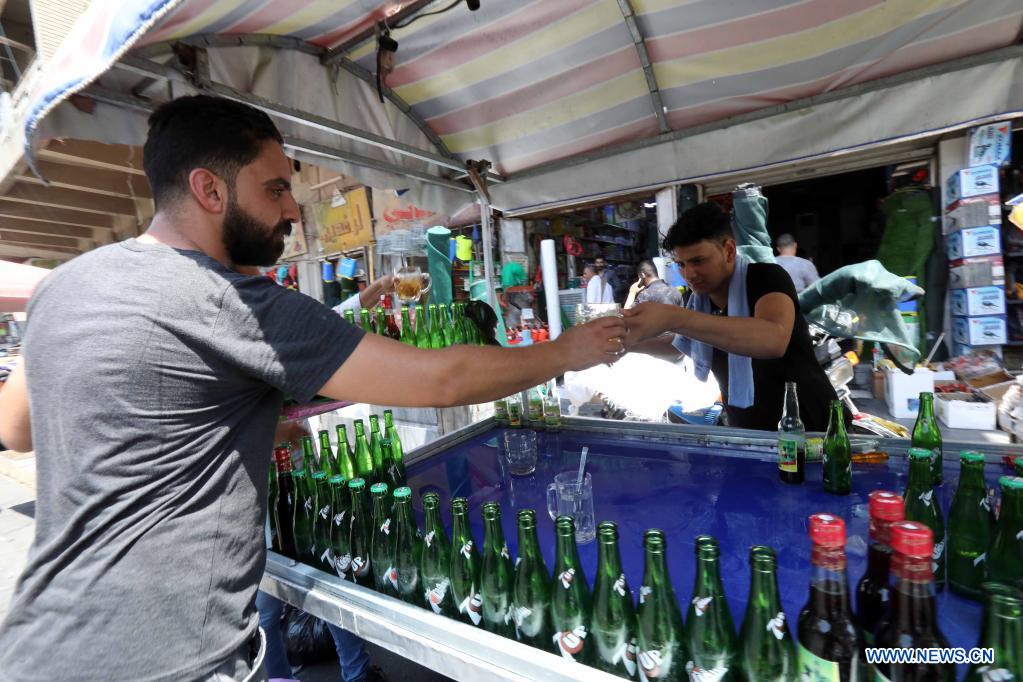 A seller hands a glass of cold drink to a customer in Baghdad, Iraq, on June 29, 2021. Scorching weather started here in June and temperatures rose to about 50 degrees Celsius. (Photo by Omar Khalil/Xinhua)