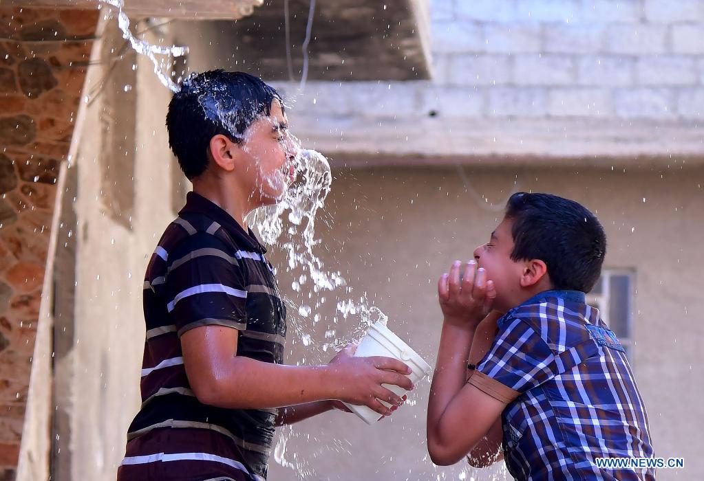 Syrian children cool off with water during hot weather in Damascus, Syria, on June 29, 2021. (Photo by Ammar Safarjalani/Xinhua)