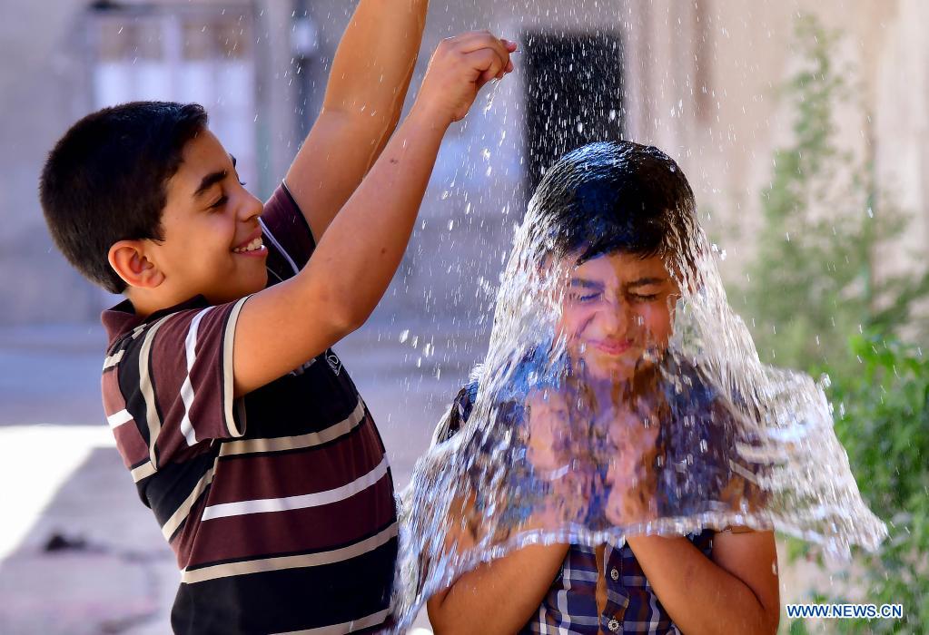 Syrian children cool off with water during hot weather in Damascus, Syria, on June 29, 2021. (Photo by Ammar Safarjalani/Xinhua)