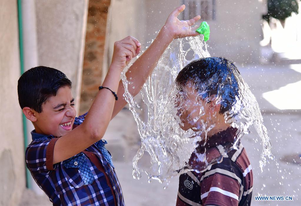 Syrian children cool off with water during hot weather in Damascus, Syria, on June 29, 2021. (Photo by Ammar Safarjalani/Xinhua)