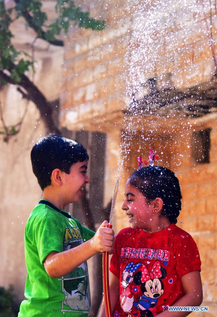 Syrian children cool off with water during hot weather in Damascus, Syria, on June 29, 2021. (Photo by Ammar Safarjalani/Xinhua)