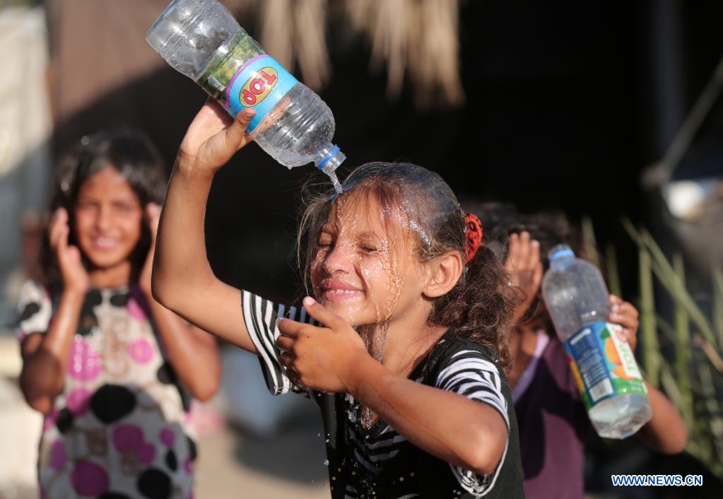 A Palestinian girl pours water to cool off during hot weather near Khan Younis refugee camp in southern Gaza Strip, on June 29, 2021. (Photo by Yasser Qudih/Xinhua)