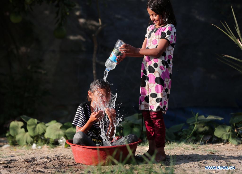 A Palestinian child is poured with water to cool off during hot weather near Khan Younis refugee camp in southern Gaza Strip, on June 29, 2021. (Photo by Yasser Qudih/Xinhua)