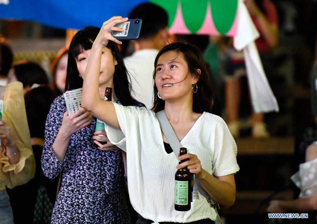People enjoy a drinking carnival in Xiqing District of north China's Tianjin, July 10, 2021. A drinking carnival called 
