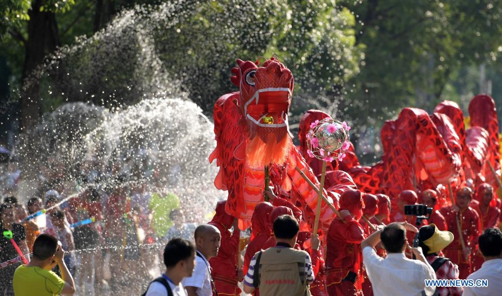 A dragon dance team performs amid splashes of water to celebrate 